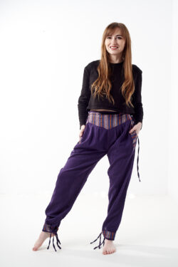 Osoba w czarnej koszulce stoi na białym tle w fioletowych spodniach z wstawkami z materiału gheri