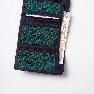 Wnętrze zielonego portfela konopnego z czarnymi elementami wykończenia, trzema mniejszymi kieszeniami, w tym jedną na zamek, oraz jedną dużą kieszenią, w której znajduje się banknot, z mniejszej kieszeni wystaje dokument tożsamości na białym tle
