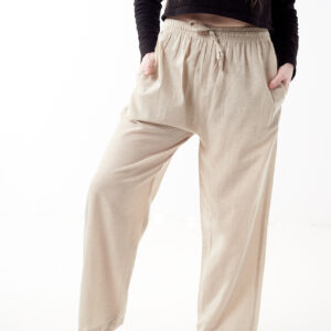 Osoba stoi na białym tle w czarnej koszulce i luźnych beżowych spodniach