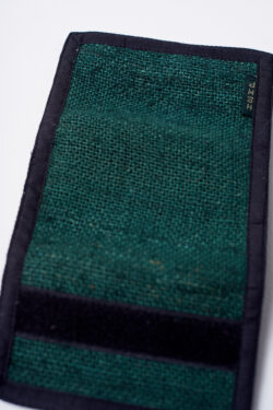 Tył zielonego portfela konopnego, częściowo rozłożony, z widocznym czarnym rzepem na krawędzi, na białym tle