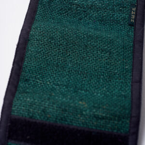 Tył zielonego portfela konopnego, częściowo rozłożony, z widocznym czarnym rzepem na krawędzi, na białym tle