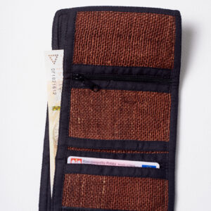 Wnętrze brązowego portfela konopnego z czarnymi elementami wykończenia, trzema mniejszymi kieszeniami, w tym jedną na zamek, oraz jedną dużą kieszenią, w której znajduje się banknot, z mniejszej kieszeni wystaje dokument tożsamości na białym tle