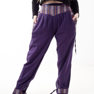 Osoba w czarnej koszulce stoi na białym tle w fioletowych spodniach z wstawkami z materiału gheri