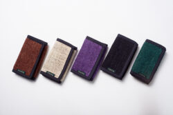Pięć portfeli z konopi ułożonych w rzędzie na białym tle w kolorach brązowym, beżowym, fioletowym, czarnym i zielonym