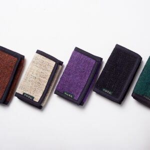 Pięć portfeli z konopi ułożonych w rzędzie na białym tle w kolorach brązowym, beżowym, fioletowym, czarnym i zielonym