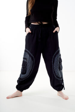 Osoba stoi na białym tle w czarno-szarych luźnych spodniach cargo z kwiatowym wzorem