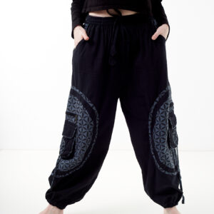 Osoba stoi na białym tle w czarno-szarych luźnych spodniach cargo z kwiatowym wzorem