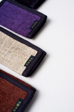 trzy portfele z konopi ułożonych w rzędzie na białym tle w kolorach brązowym, beżowym i fioletowym