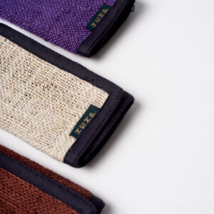 trzy portfele z konopi ułożonych w rzędzie na białym tle w kolorach brązowym, beżowym i fioletowym