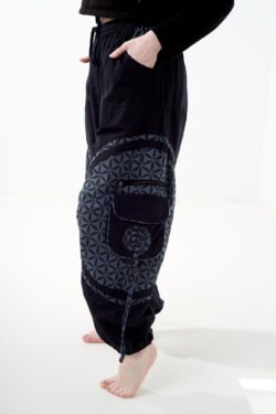 Osoba stoi bokiem na białym tle w czarno-szarych spodniach cargo z kwiatowym wzorem.