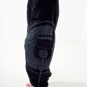 Osoba stoi bokiem na białym tle w czarno-szarych spodniach cargo z kwiatowym wzorem.