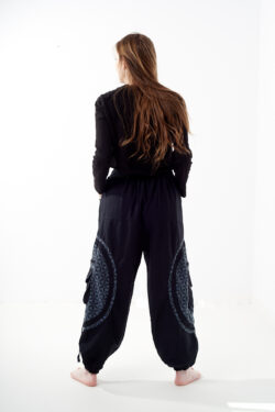 Osoba stoi tyłem na białym tle w czarno-szarych spodniach cargo z dużymi kieszeniami i kwiatowym wzorem