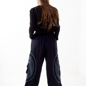 Osoba stoi tyłem na białym tle w czarno-szarych spodniach cargo z dużymi kieszeniami i kwiatowym wzorem