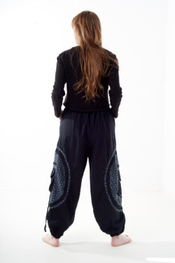 Osoba stoi tyłem na białym tle w czarno-szarych spodniach cargo z dużymi kieszeniami i kwiatowym wzorem