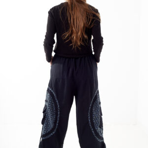 Osoba stoi tyłem na białym tle w czarno-szarych spodniach cargo z dużymi kieszeniami i kwiatowym wzorem