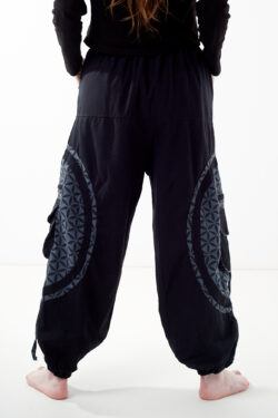 Osoba stoi tyłem na białym tle w czarno-szarych spodniach cargo z dużymi kieszeniami i kwiatowym wzorem